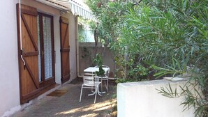 A small patio with a table and chairs, a wooden door, and a concrete wall. - Single room 2 person motel 2 (Porto-Vecchio)