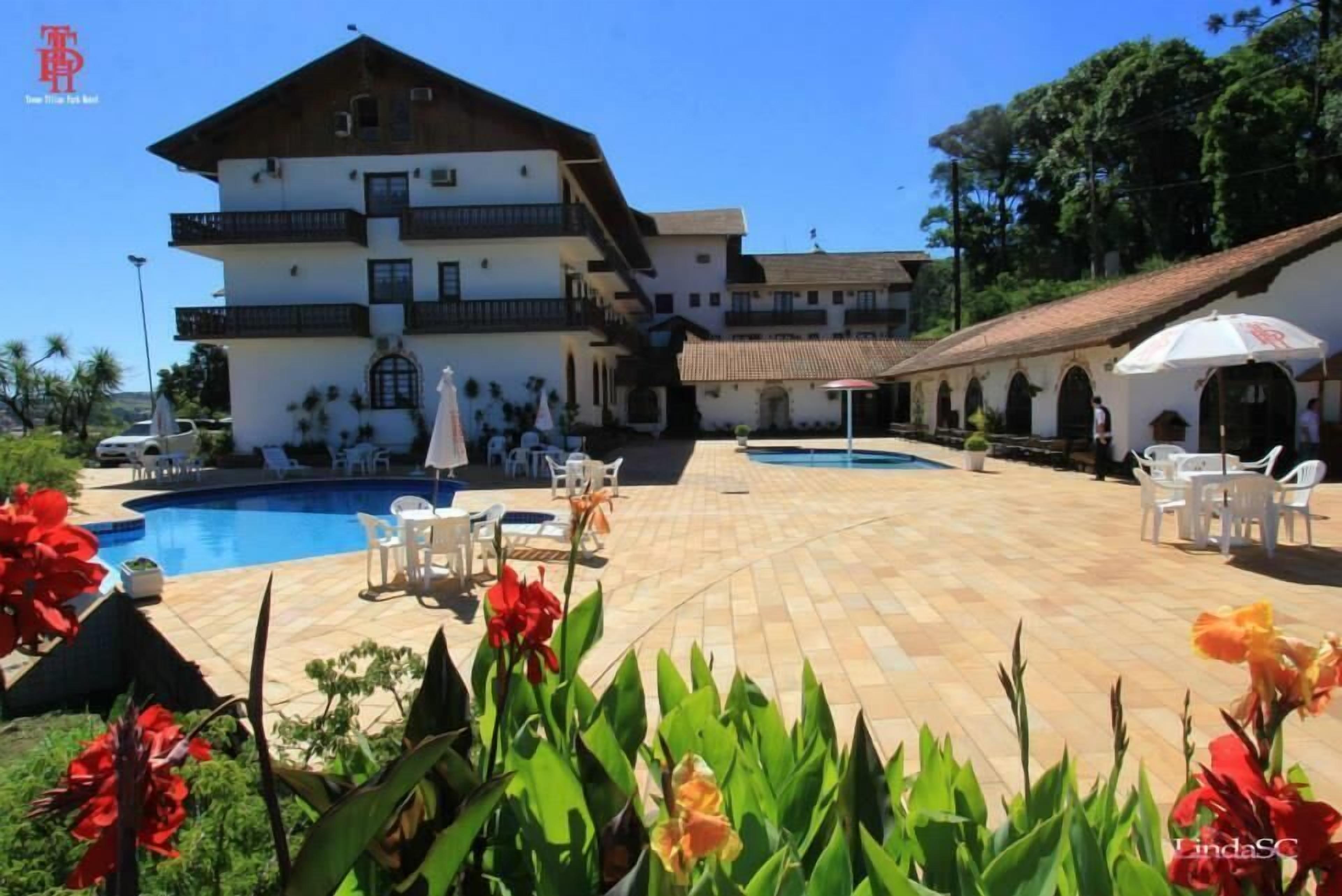 Ein Hotel mit Schwimmbad, Außenbereich zum Sitzen und einem großen Gebäude mit mehreren Balkonen.