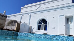 A white building with a pool, a window, and a door. - Loukas Kontos Traditional House (Santorini)