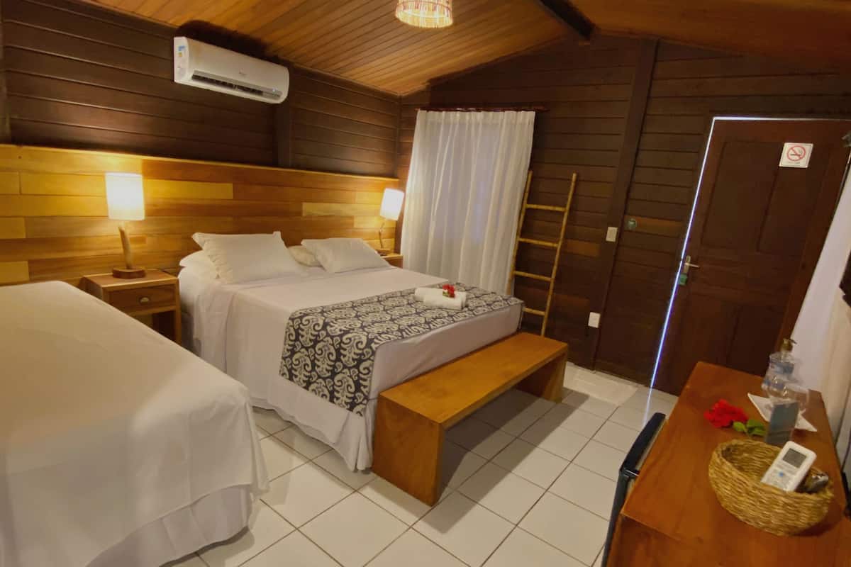 Una habitación con paneles de madera, dos camas, un banco, un escritorio y una lámpara colgante.
