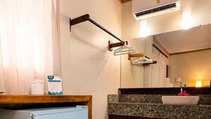 A compact kitchen with a refrigerator, a sink, and a wooden stool.