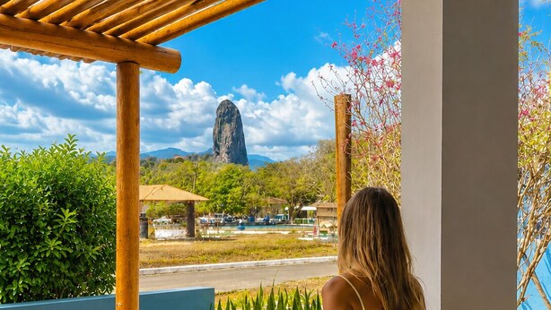 A wooden deck with a bench, a view of a mountain, and a statue.