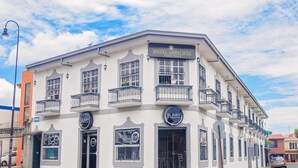 A white building with balconies, a sign for Hotel Arrecifes, and a sign for El Adri Bar y Restaurante. - Hotel Arrecifes (San José)