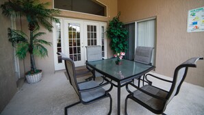 A glass-top table with four chairs, a potted plant, and a poster on the wall. - Florida Disney Vacation rental (Kissimmee)