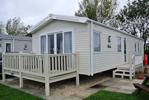 A mobile home with a deck, a small porch, and a fire extinguisher.