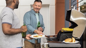 Two people near a grill with a plate of food and a bottle. - Candlewood Suites Jacksonville - Mayport by IHG (Atlantic Beach)