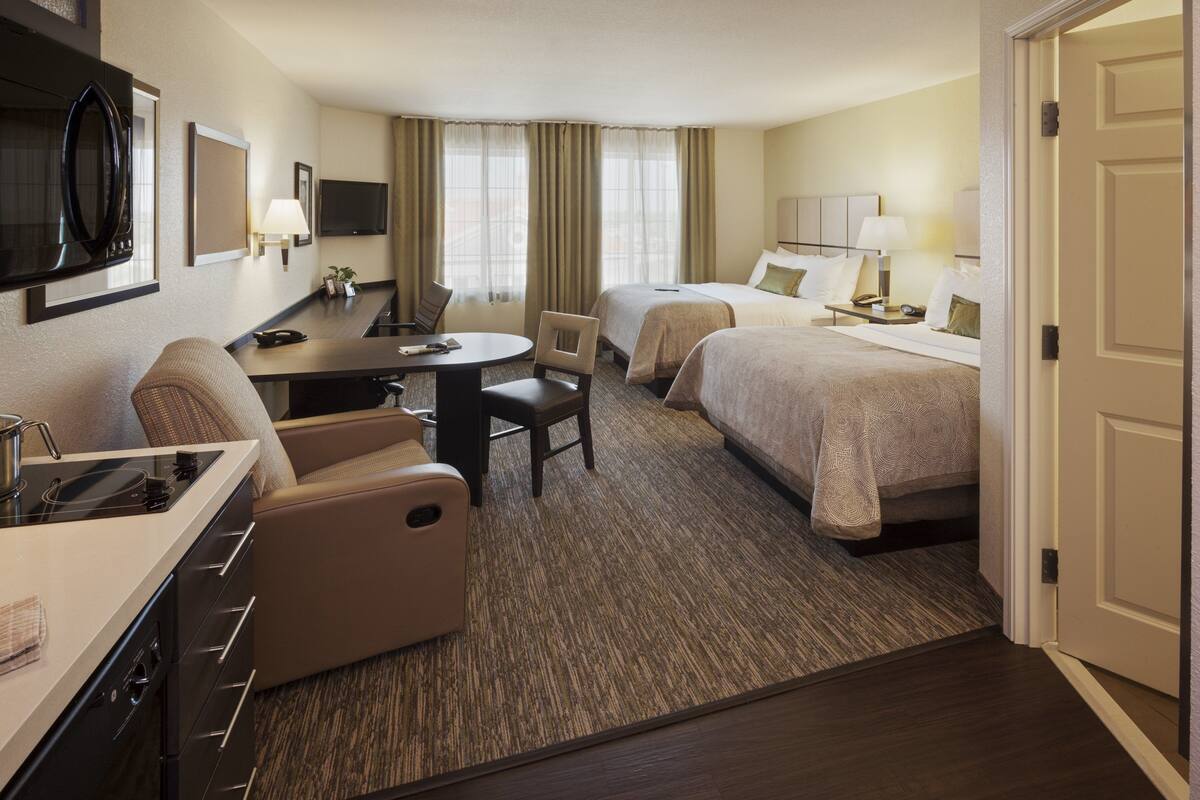 Une chambre d’hôtel avec un coin repas, deux lits, une télévision et une kitchenette.
