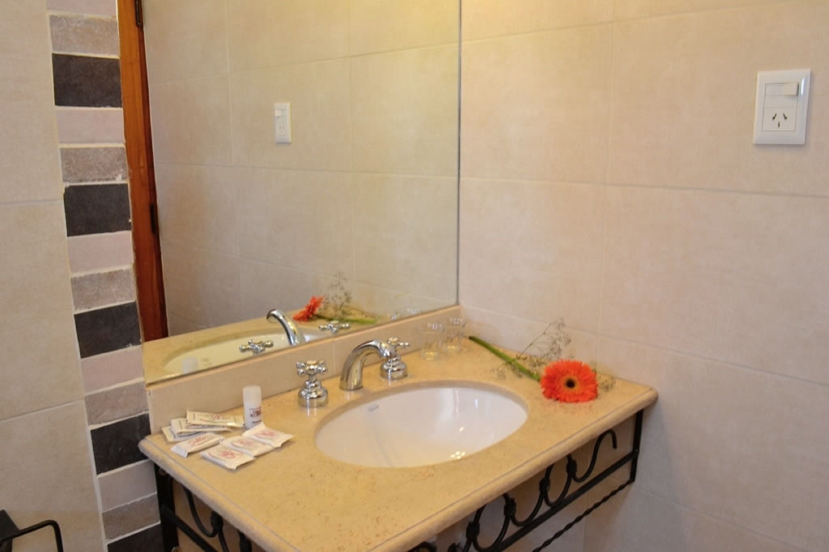 Un baño con lavabo, espejo y perchero para toallas.