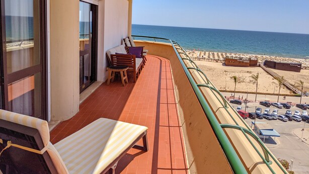 Un balcon avec vue sur la plage, une table, des chaises et un canapé.