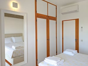 A hotel room with a bed, a mirror, and a wardrobe.