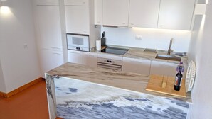 Une cuisine moderne avec des meubles blancs, un plan de travail en marbre, un four encastré et un évier.