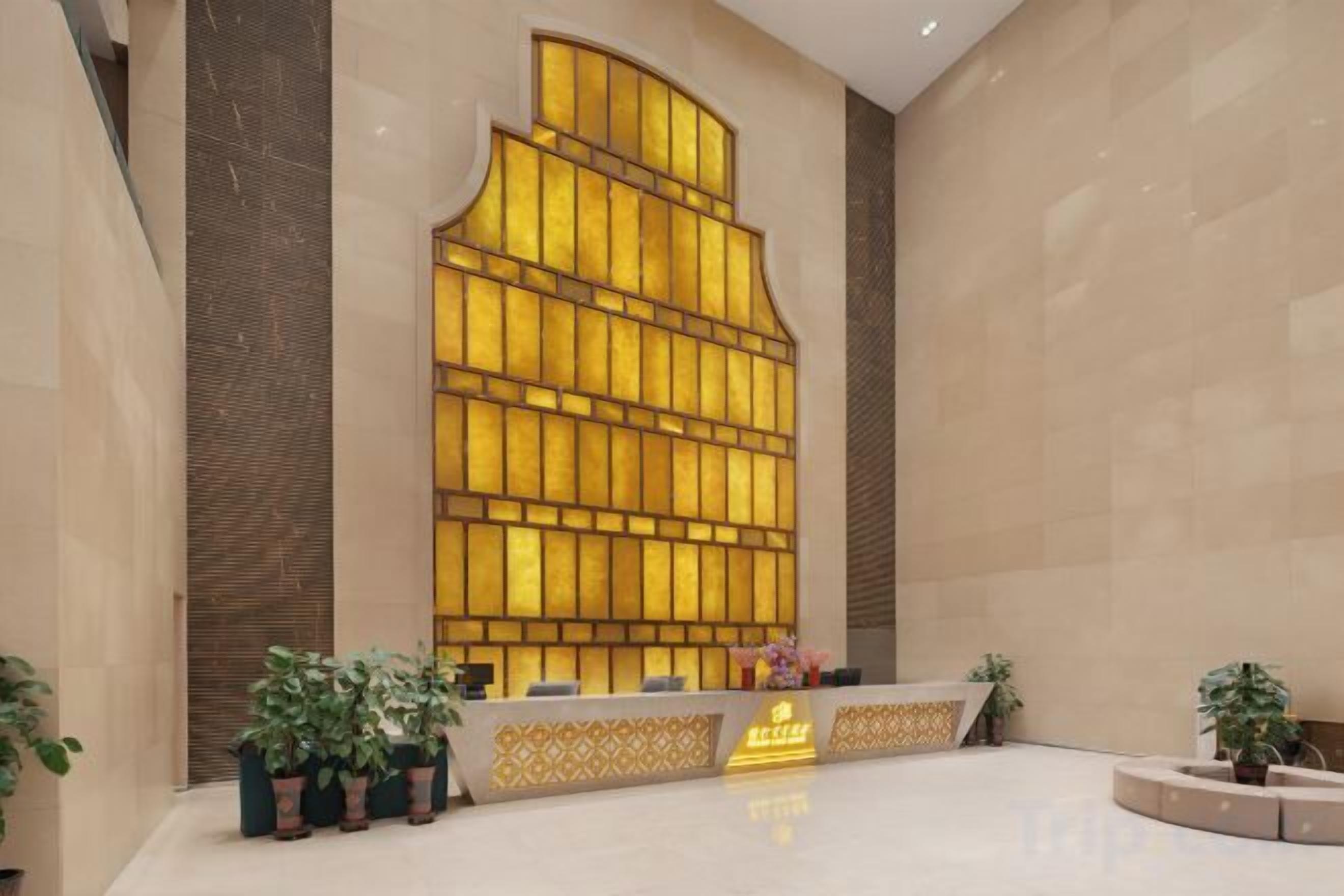 A reception area with a large, illuminated wall feature, a reception desk, and potted plants.