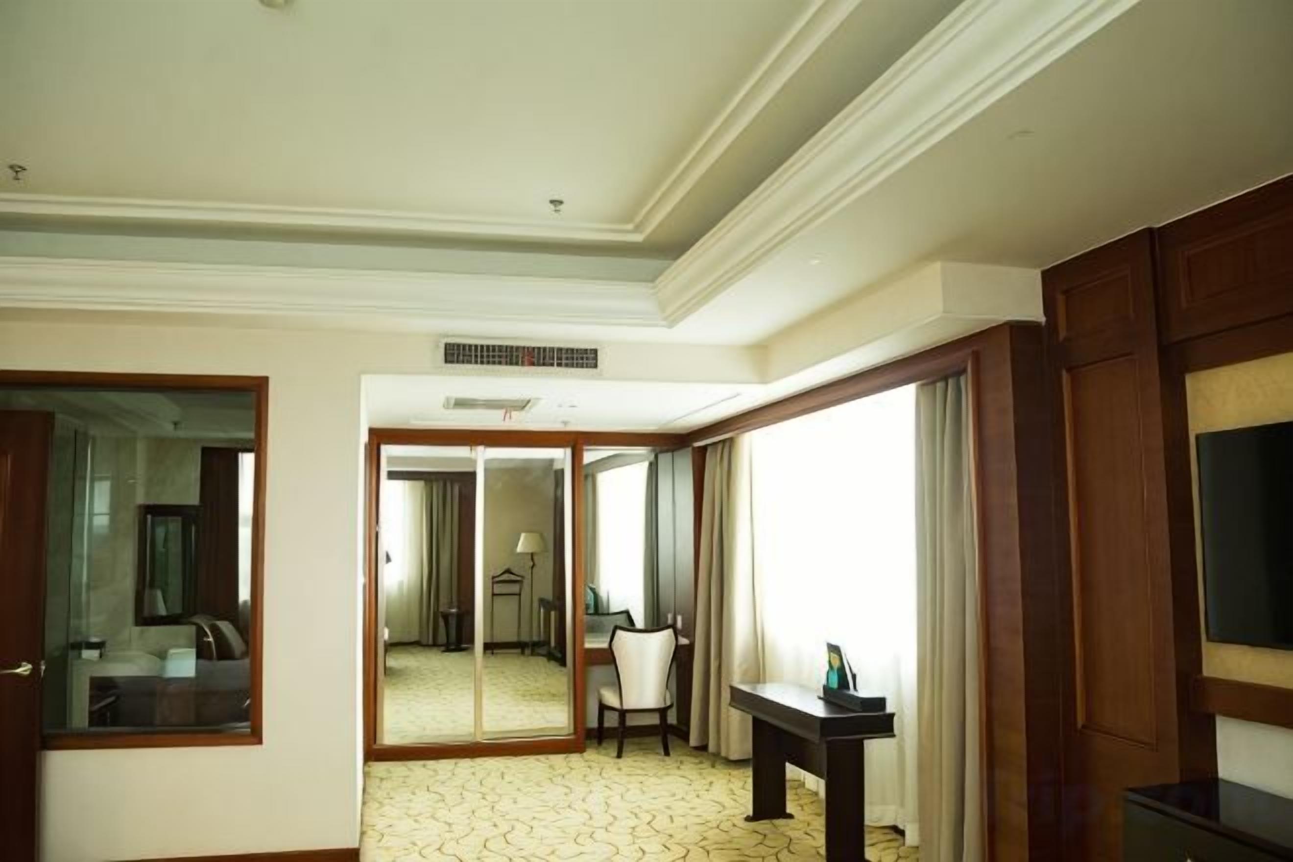 Une chambre d’hôtel avec un grand miroir, un lit, un bureau et une télévision.