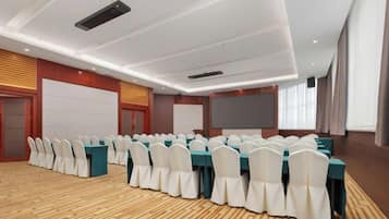 A conference room with rows of tables and chairs, a whiteboard, and a projection screen.