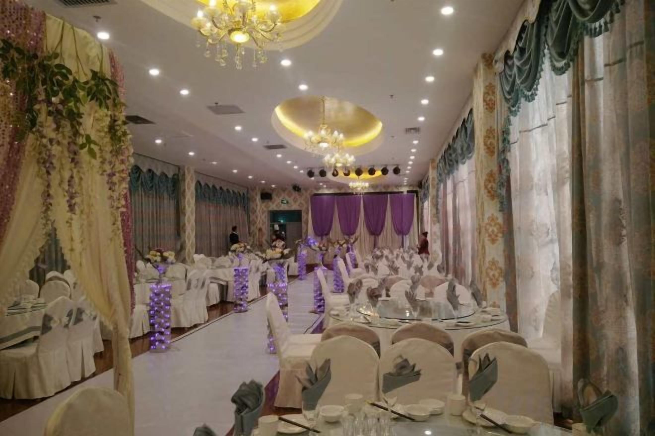 A banquet hall with round tables, chairs, and a chandelier.