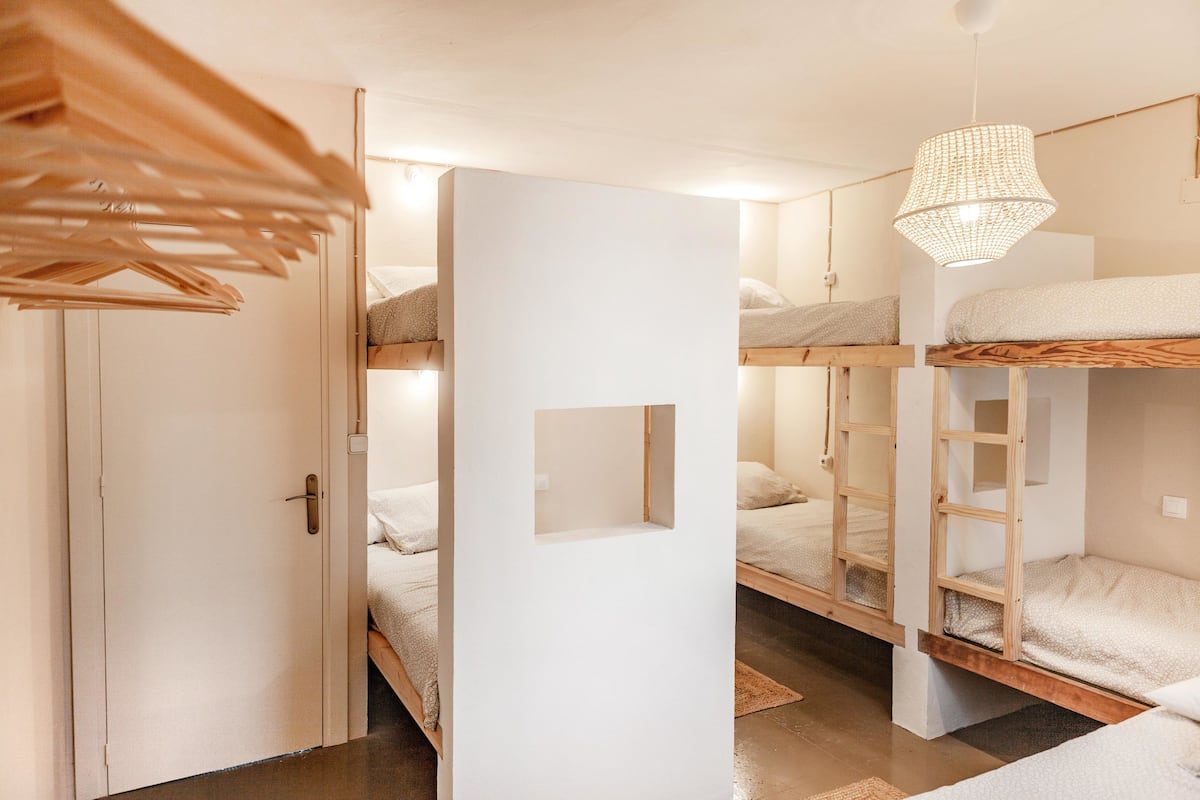 A compact room with bunk beds, a wooden door, and a hanging light fixture.