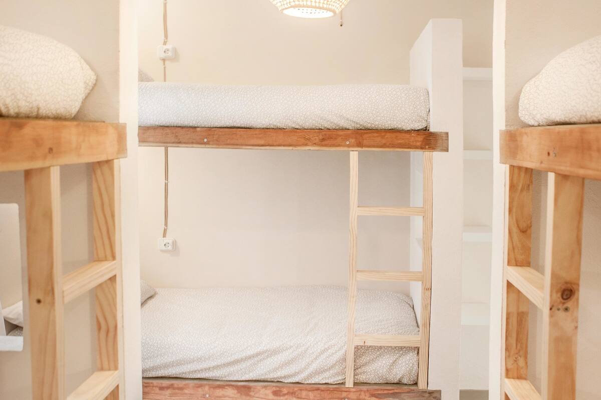 A bunk bed room with a woven light fixture above.