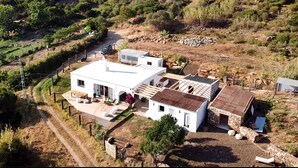 A white two-story house with a patio, a stone structure, and a fenced garden. - Wild House Tarifa - Hostel (Tarifa)