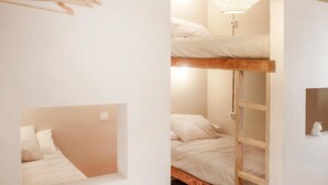 A bunk bed room with a hanging light fixture and a white wall with a picture frame. - Wild House Tarifa - Hostel (Tarifa)