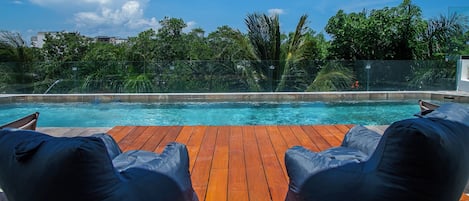 A poolside area with two lounge chairs and a wooden deck.