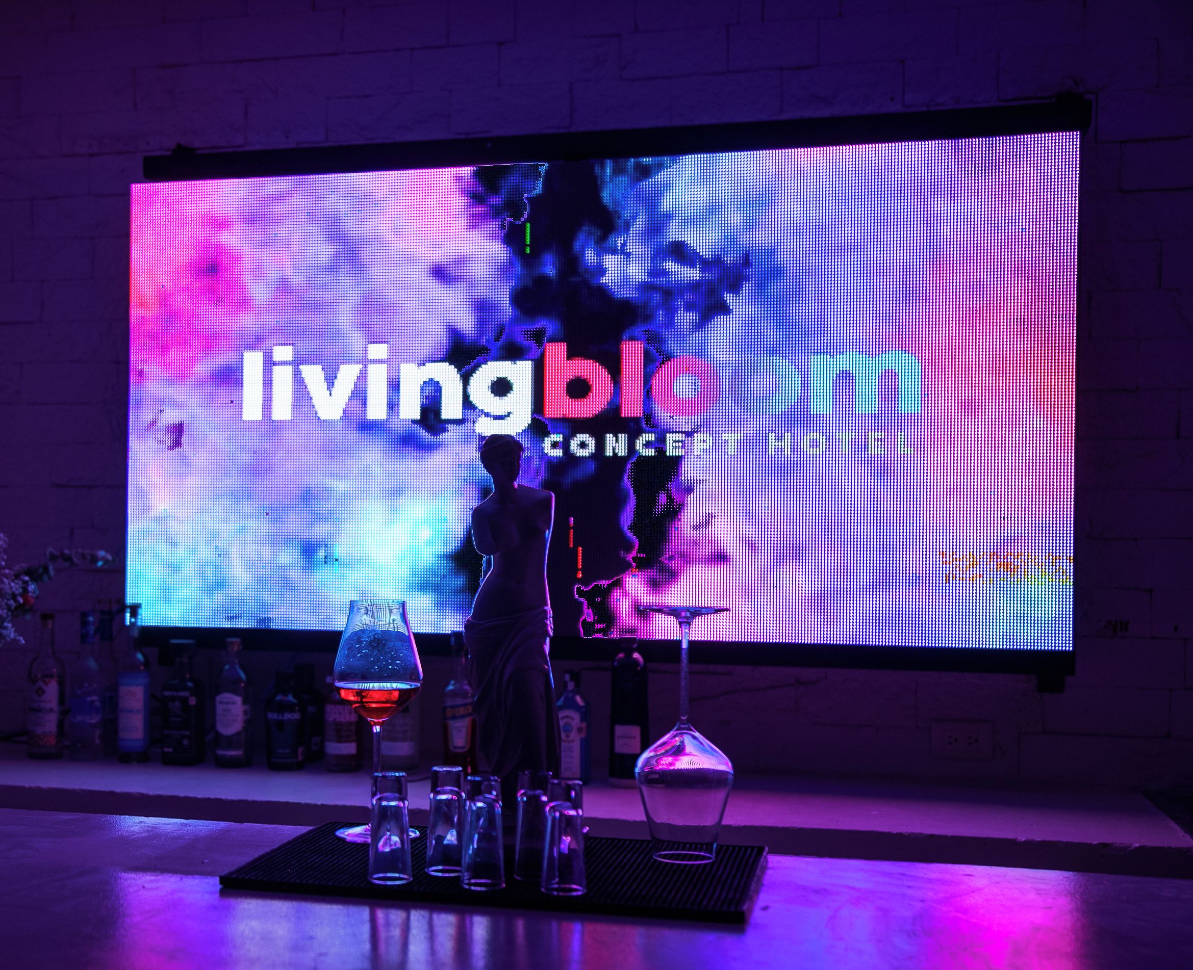 A bar area with a large LED screen displaying 'livingblc CONCEPT HOTEL' and a bartender's silhouette.
