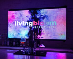 Zona de bar con una gran pantalla LED mostrando 'livingblc CONCEPT HOTEL' y la silueta de un camarero.