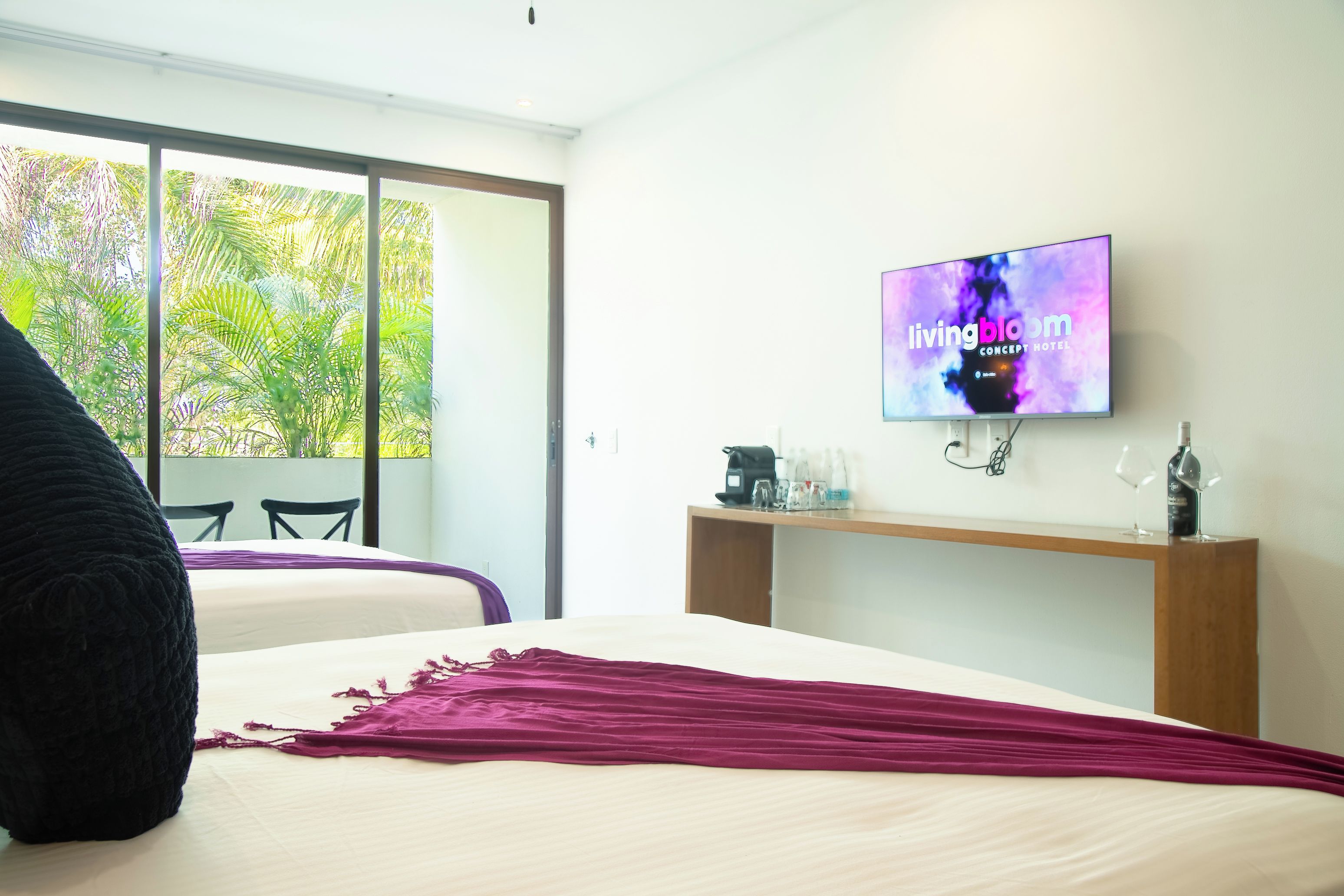 Een hotelkamer met een bed, een televisie aan de muur, een koffieapparaat en uitzicht op groen.