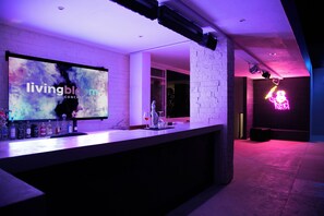 A bar area with a digital screen displaying 'livingbl' and a neon skeleton sign. - Living Bloom, Concept Hotel  (Tulum)