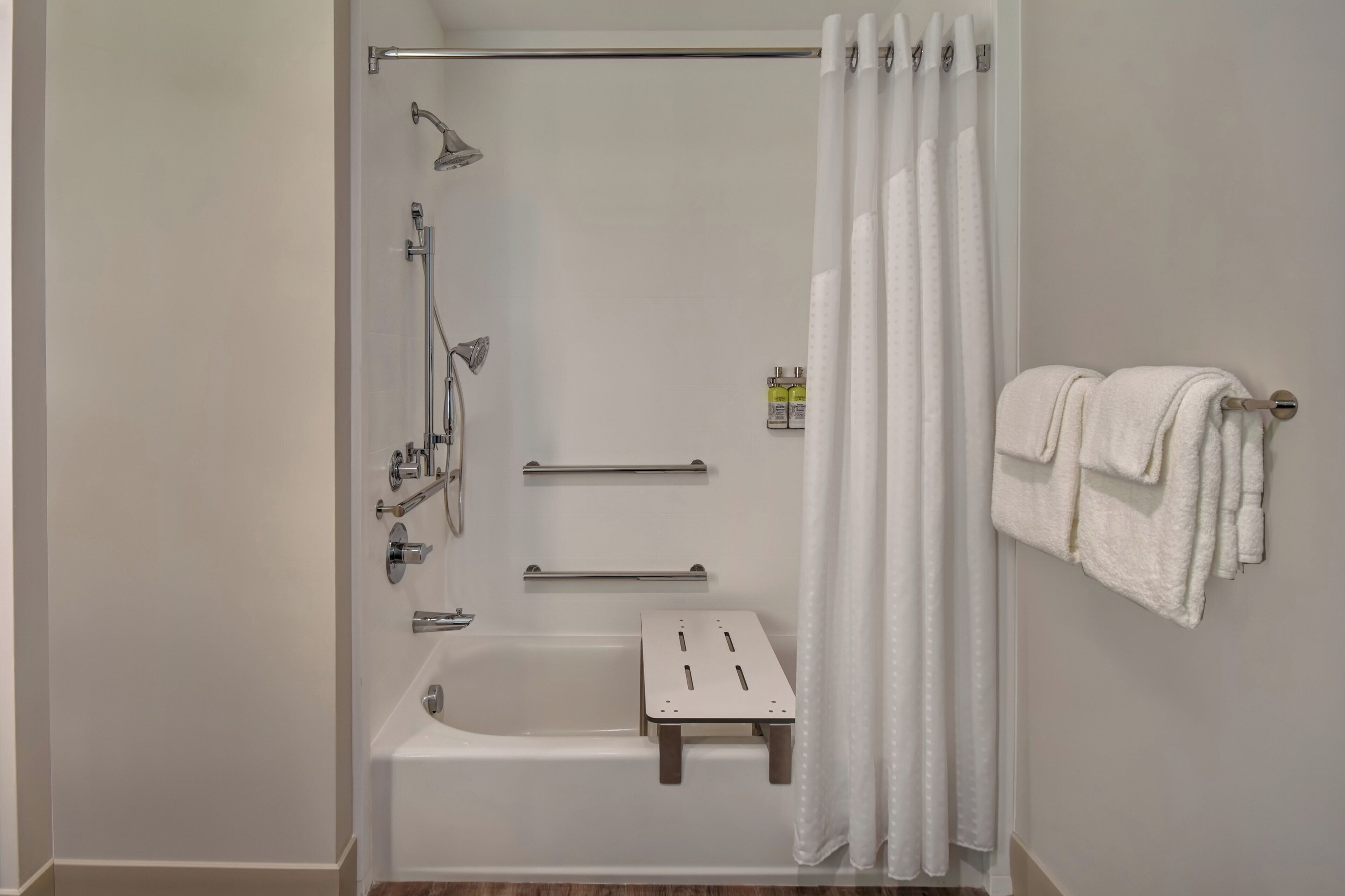 A modern bathroom with a walk-in shower, a bathtub, and a towel rack.