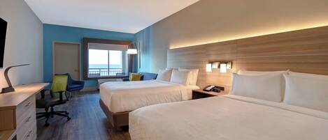 A hotel room with two beds, a desk, a chair, a phone, and a window with a view.