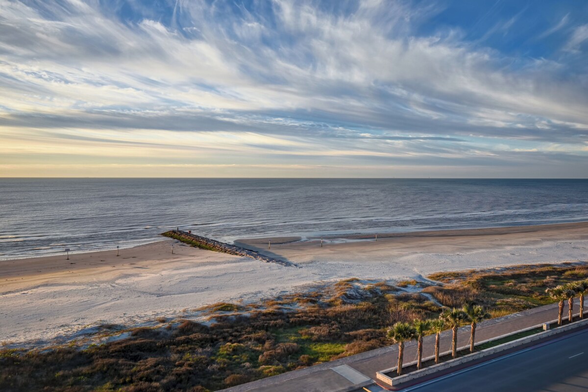 A coastal road with a beach and palm trees.