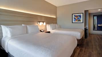 A hotel room with two beds, a wooden headboard, a wall-mounted light, and a framed abstract painting.