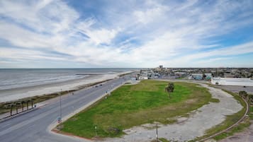 A coastal road with a grassy area and a view of the ocean and cityscape.