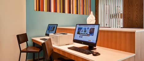 Taulell de recepció d'hotel amb dos ordinadors, una impressora i un dispensador de mocadors.