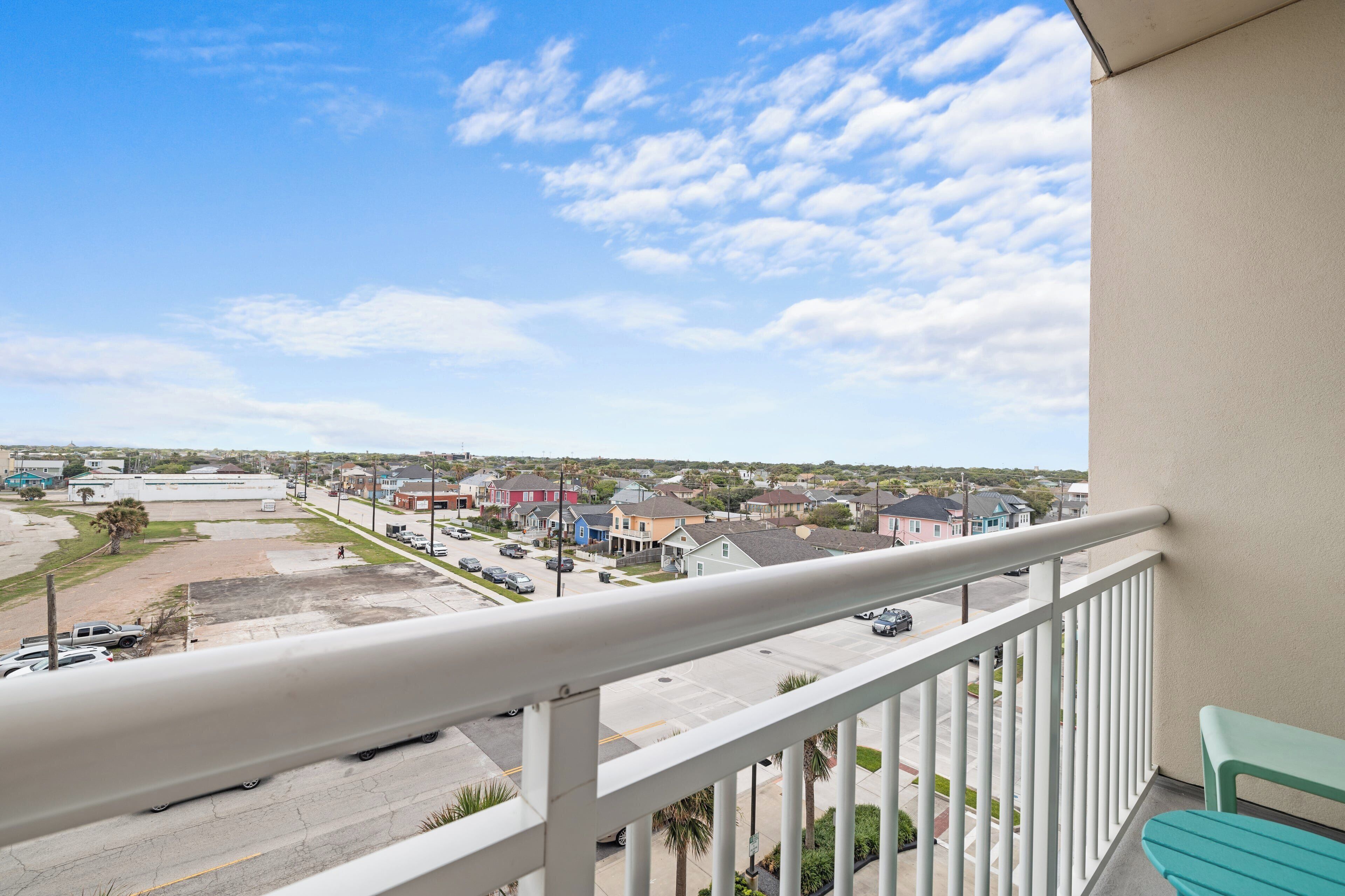 Un balcon donnant sur un quartier résidentiel, avec vue sur des maisons et un parking.