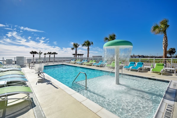 Relax by the pool surrounded by palm trees and a soothing water feature.