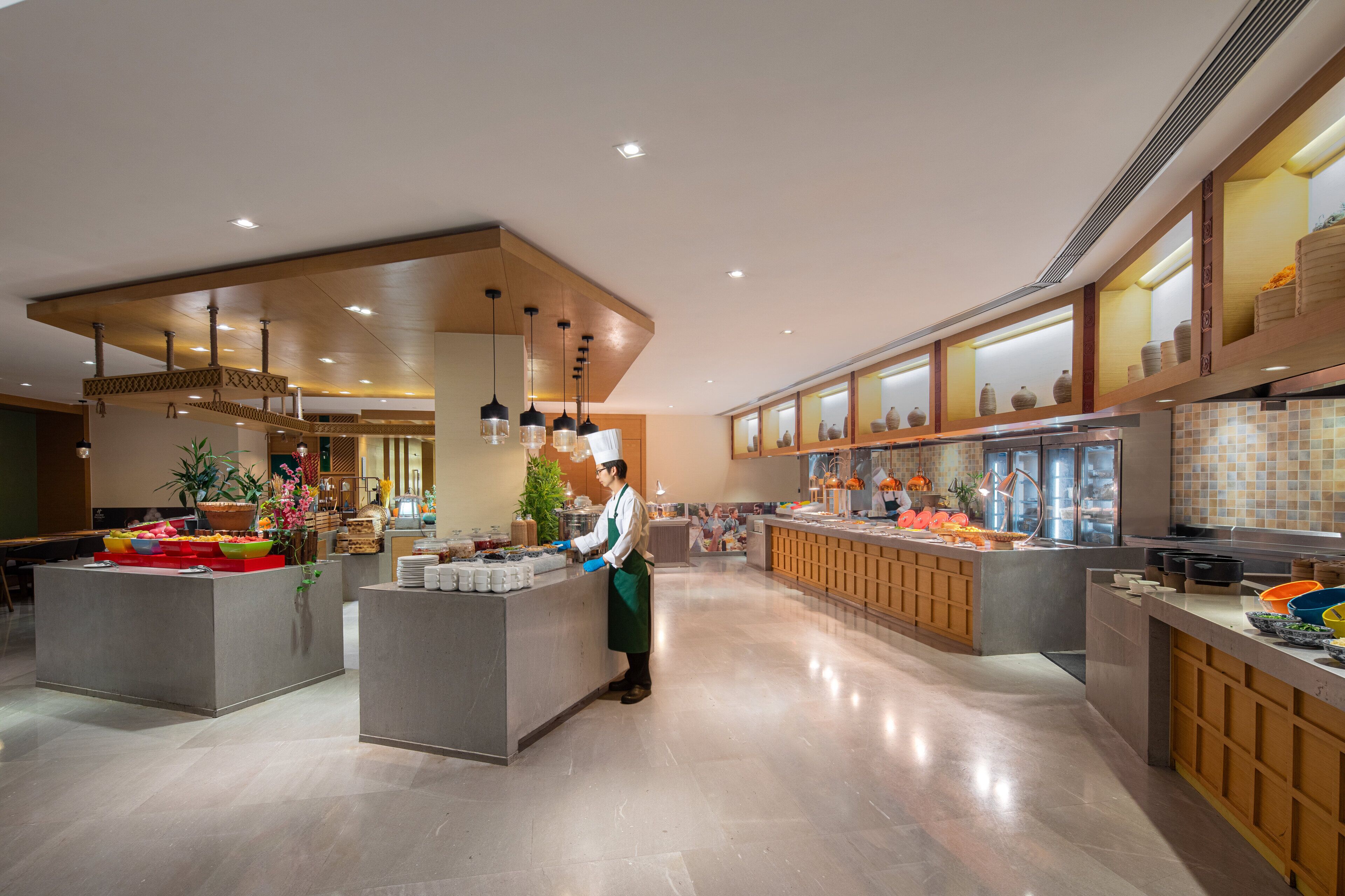 A spacious hotel kitchen with modern design, featuring a central island, multiple serving stations, and a variety of kitchen equipment.
