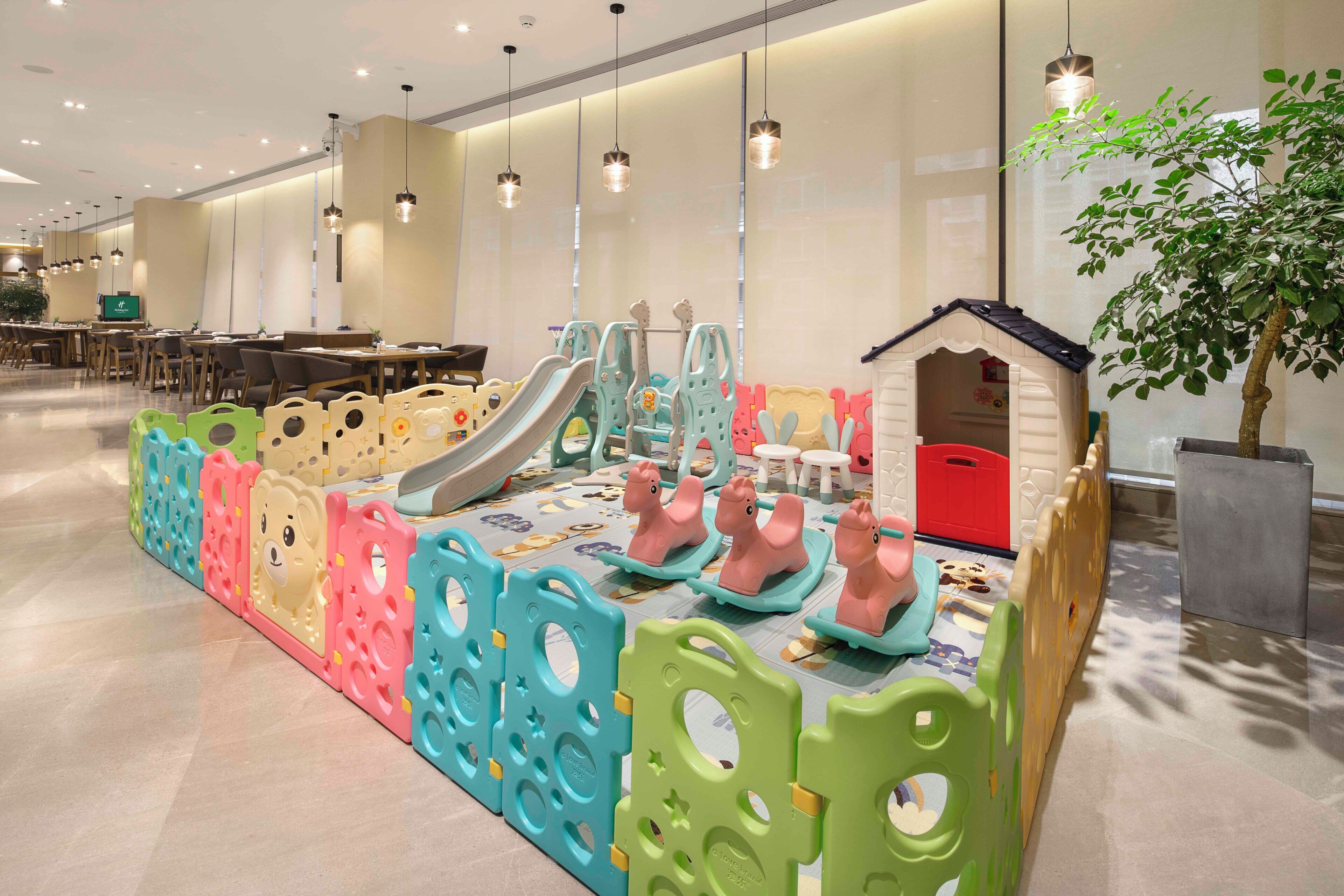 Zona de juegos infantiles con tobogán, estructuras de juego y una casita.