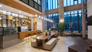 Un intérieur spacieux et moderne, avec une longue table en bois, des sièges confortables et une grande fenêtre donnant sur l’extérieur.