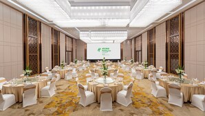 Une salle de conférence avec des tables rondes, des chaises blanches et des centres de table ornés de fleurs.