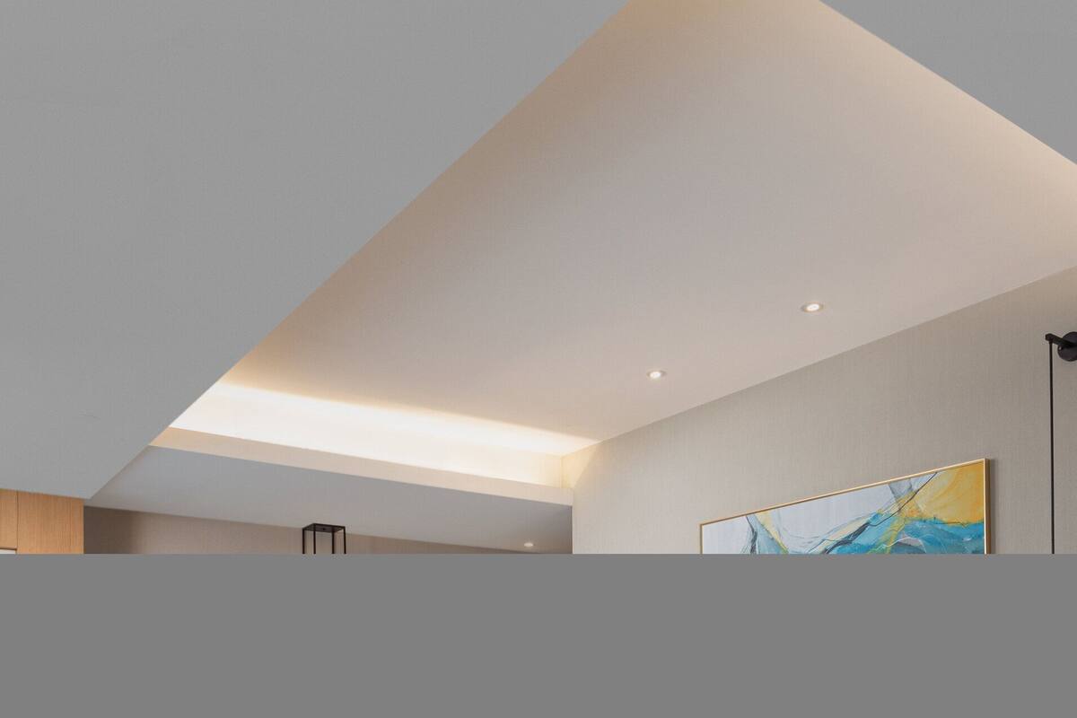 A modern interior with a sloped ceiling, recessed lighting, and a large abstract painting on the wall.