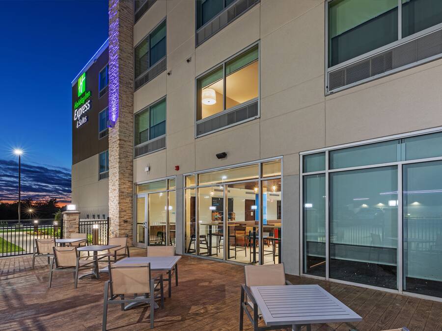 A hotel exterior with outdoor seating, large windows, and a visible sign for the hotel.