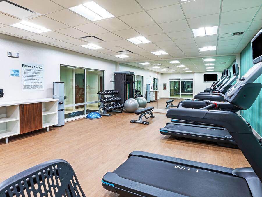 Un gimnasio con cintas de correr, máquinas de pesas y pelotas de ejercicio.