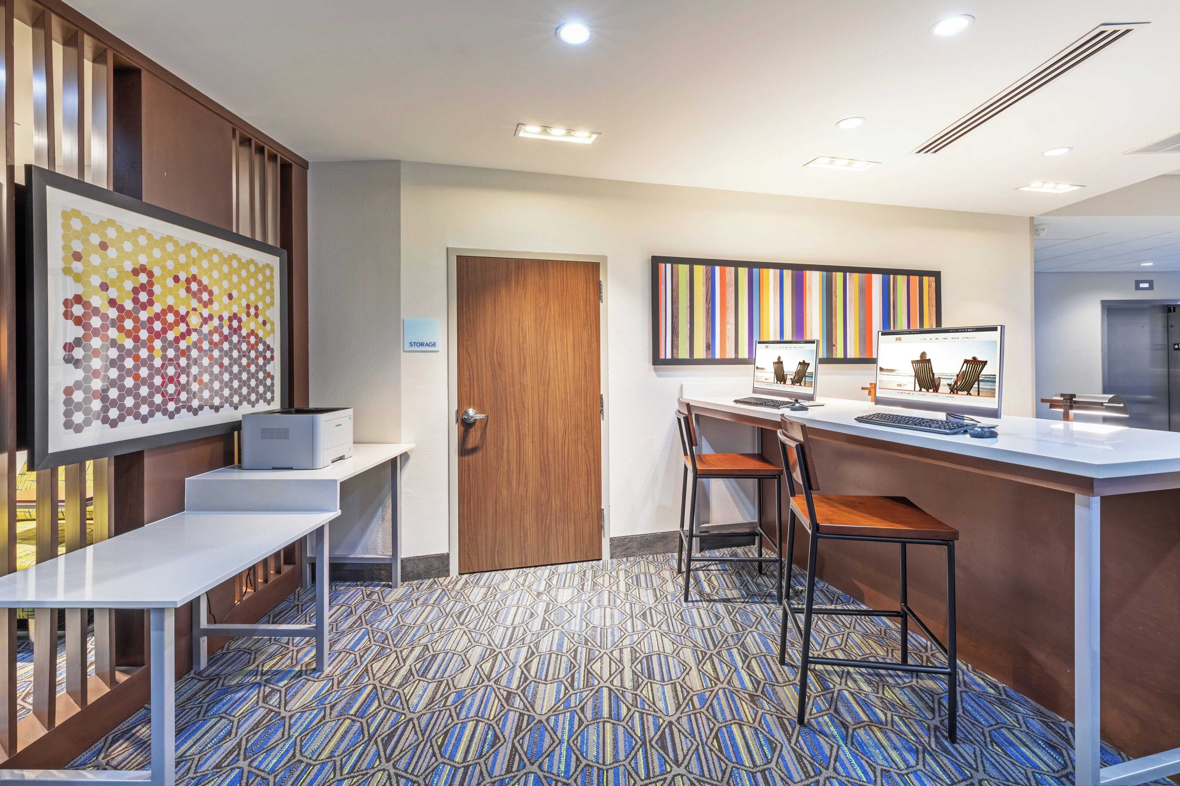 A modern office space with a desk, chairs, a computer, and a printer.