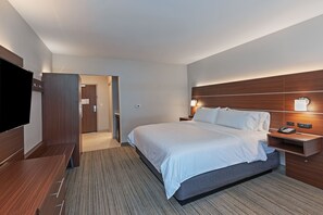 A hotel room with a large bed, a TV, a wooden headboard, and a bedside table with a lamp. - Holiday Inn Express & Suites Parsons by IHG (Parsons)