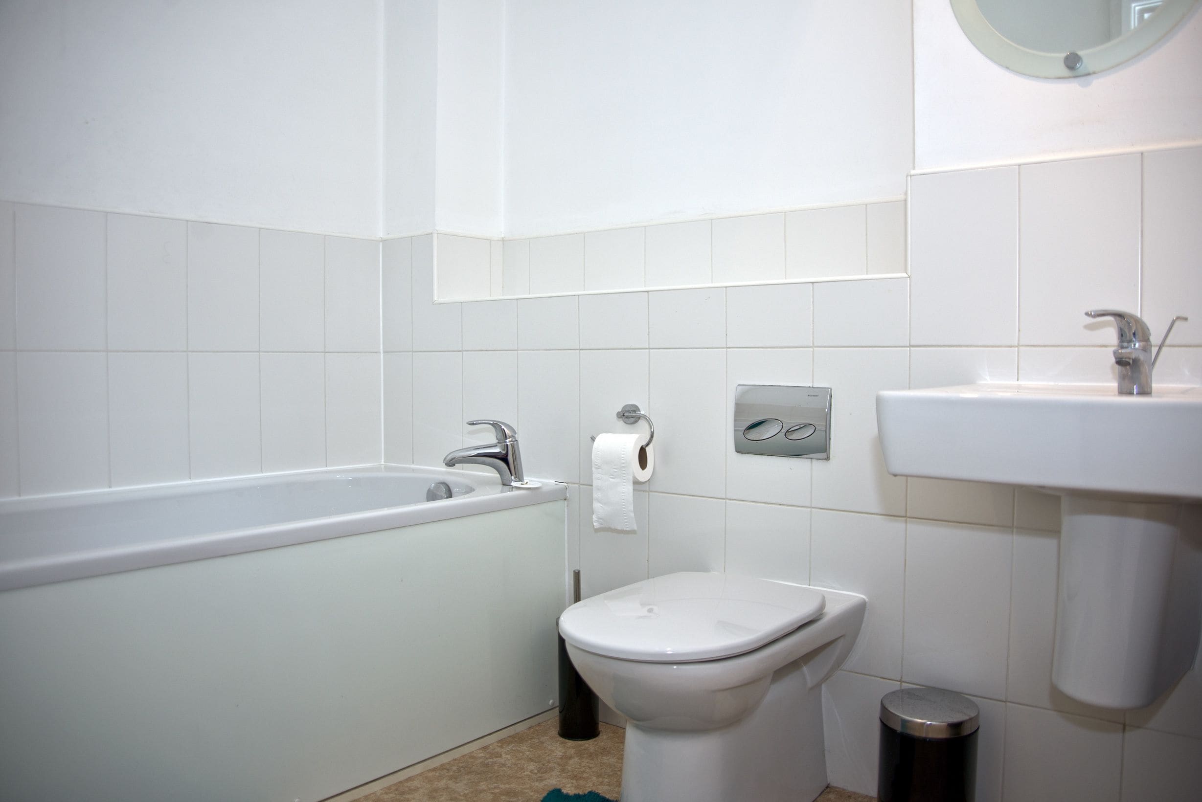 Un bagno con una vasca, un water, un lavandino e un cestino.