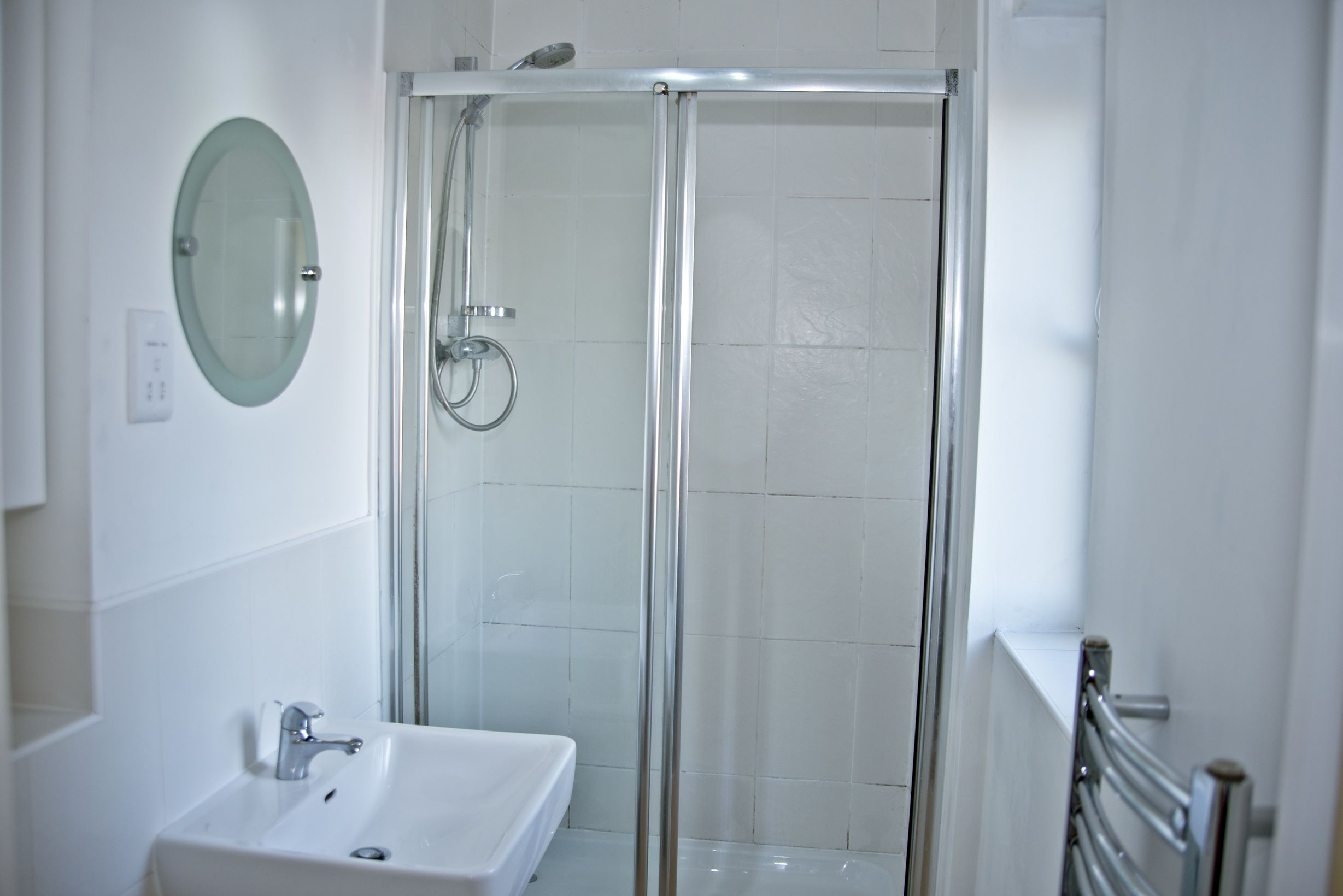 Une salle de bain moderne avec une douche à parois de verre, un lavabo blanc et un miroir.