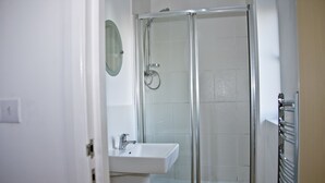Une salle de bain avec une douche à parois de verre, un lavabo blanc et un miroir.