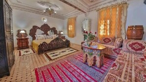 A traditional room with a bed, a sofa, a coffee table, and a decorative mirror. - Riad la porte bleue du palais laraichi (Fes)