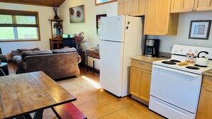Una cocina acogedora con armarios de madera, un refrigerador blanco, una estufa y una mesa de comedor con bancos.